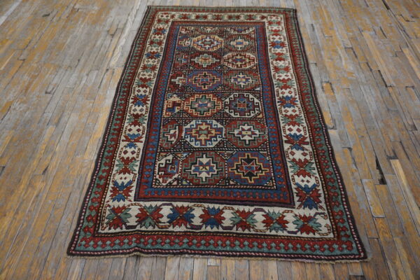 Red, blue, and cream tribal rug with geometric designs laid across distressed wood flooring.
