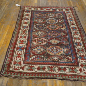 Geometric red, blue, and cream medallion rug centered on a distressed yellow hardwood floor.