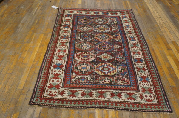 Geometric red, blue, and cream medallion rug centered on a distressed yellow hardwood floor.