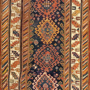 Detailed geometric rug with a navy field, rust medallions, and multi-layered borders in cream, blue, and gold.