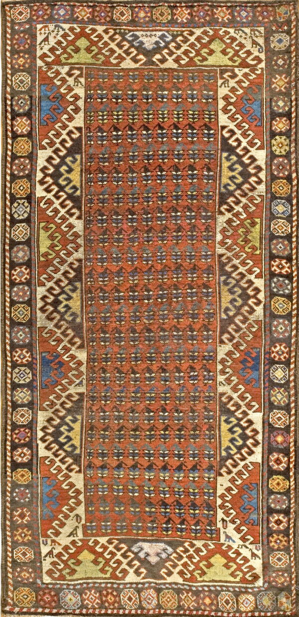 Rectangular rug featuring a terracotta field, repeating dark motifs, and wide multicolored geometric borders.