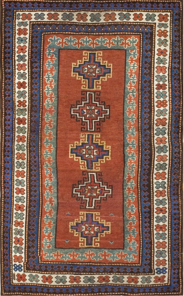 Flat-weave rug with a rust field, featuring stacked blue geometric motifs and elaborate teal and brown borders.