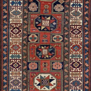 A runner rug with repeating geometric medallions in red, navy blue, and cream borders.