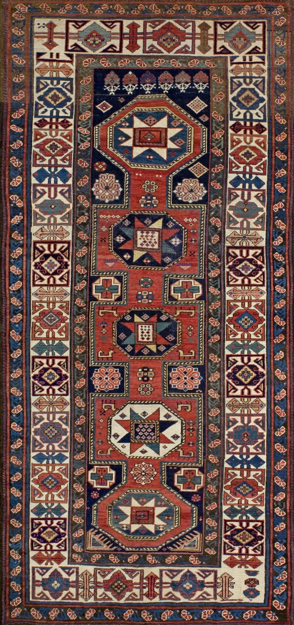 A runner rug with repeating geometric medallions in red, navy blue, and cream borders.