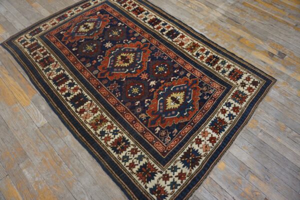 Navy and rust geometric rug with complex borders resting on distressed gray wood flooring.