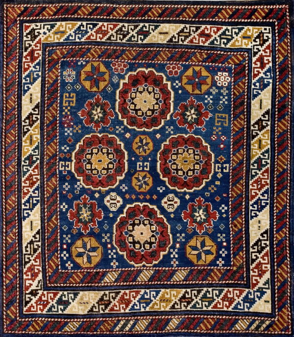 Deep blue rug with geometric red, gold, and cream medallions surrounded by intricate multicolored borders.