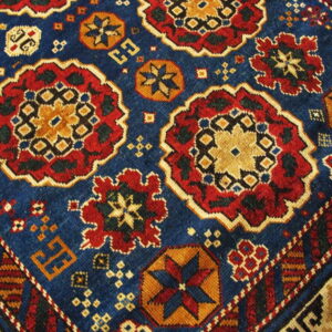 Geometric rug pattern featuring large red and gold medallions on a dark blue field with a detailed striped border.