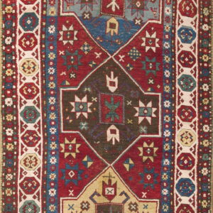 Stepped geometric runner rug in red, blue, and tan, framed by a wide border of repeating octagons.