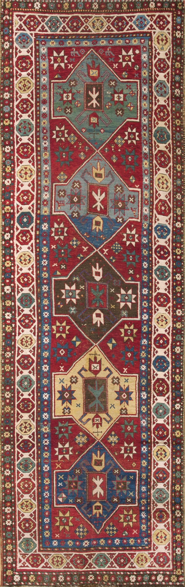 Stepped geometric runner rug in red, blue, and tan, framed by a wide border of repeating octagons.