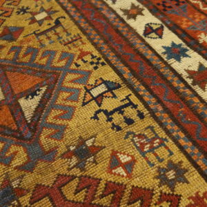 Geometric patterned rug with a textured surface, featuring colors of gold, rust, blue, and cream.