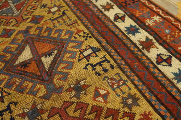Geometric patterned rug with a textured surface, featuring colors of gold, rust, blue, and cream.