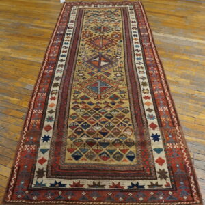 Multicolored geometric runner rug with a low pile lies on distressed wood plank flooring.