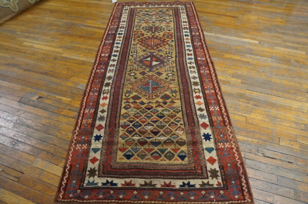 Multicolored geometric runner rug with a low pile lies on distressed wood plank flooring.