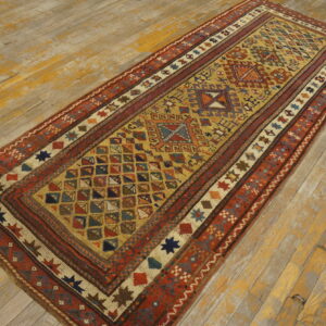 Geometric runner rug in gold, red, and blue colors rests on distressed hardwood flooring.