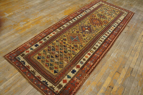 Geometric runner rug in gold, red, and blue colors rests on distressed hardwood flooring.