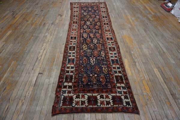 Traditional navy runner rug with red and cream geometric patterns on distressed wood planks.