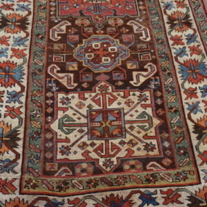 Geometric traditional rug with a deep brown center field and thick cream and green patterned borders.