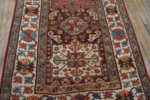 Geometric traditional rug with a deep brown center field and thick cream and green patterned borders.