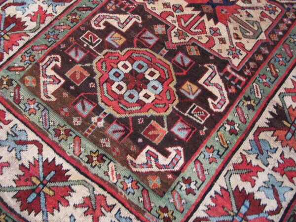 Detailed geometric rug pattern in deep brown, vibrant red, teal, and light cream colors.