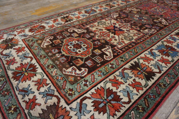 Ornate patterned rug in dark brown, ivory, rust, and teal green on weathered wood planks.