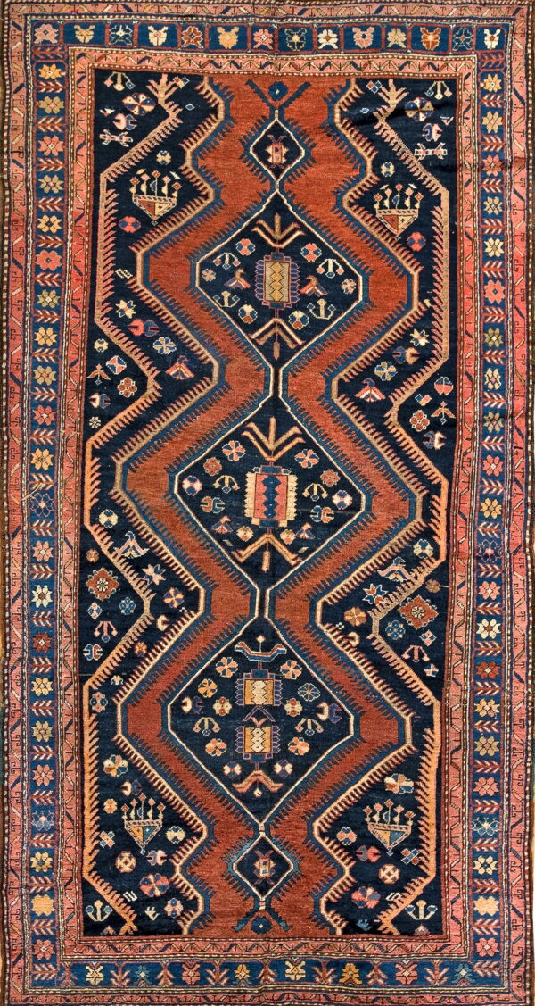 Traditional rug with a navy and rust geometric pattern featuring stacked medallions and a floral border.