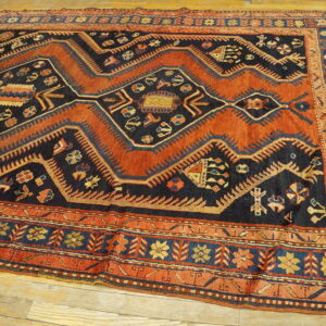 Geometric pattern rug featuring deep rust and navy blue colors, laid on light hardwood flooring.