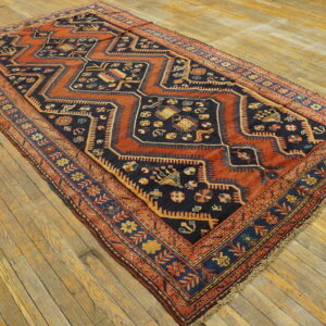 Rectangular navy and rust rug with stepped geometric medallions and patterned borders on wood floor.