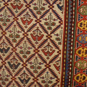 Beige rug field featuring red and blue stylized bird motifs and a thick colorful border with medallions.