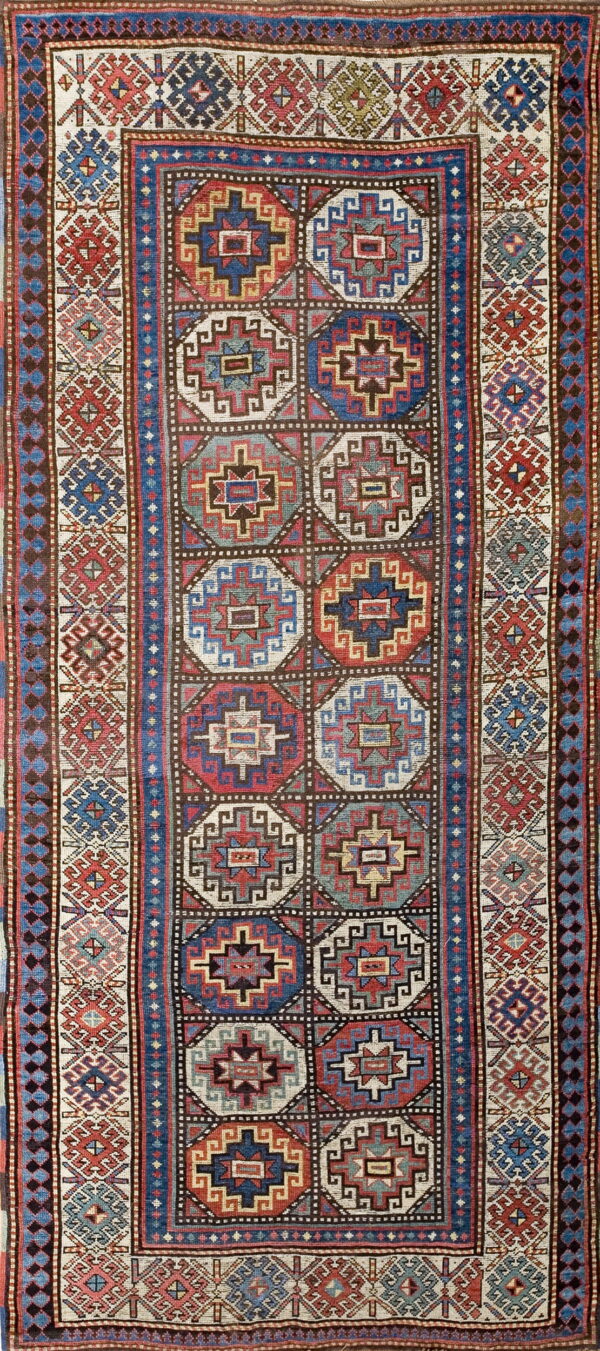 A geometrically patterned rug featuring columns of multicolored octagonal medallions and intricate blue and red borders.