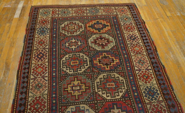 Low-pile rug with geometric medallions in muted red, navy, and cream on a light honey wood floor.