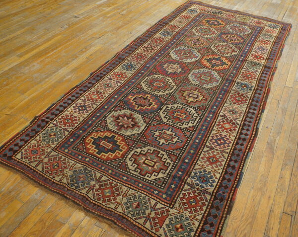 Geometric runner rug in red, navy, and cream patterns on a distressed golden wood floor.
