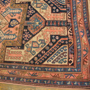 Low-pile rug with complex pink, navy, and cream geometric designs on light wood flooring.