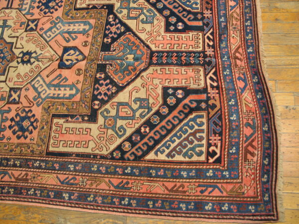 Low-pile rug with complex pink, navy, and cream geometric designs on light wood flooring.