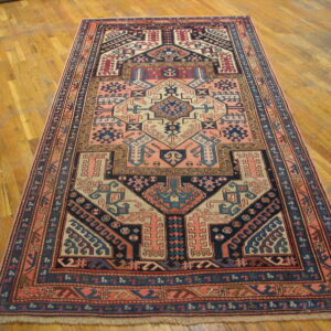 Traditional geometric rug featuring navy, coral, and cream patterns on a golden hardwood floor.