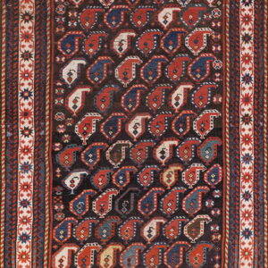 Low pile rug featuring repeating red, navy, and cream boteh designs on a deep brown field.