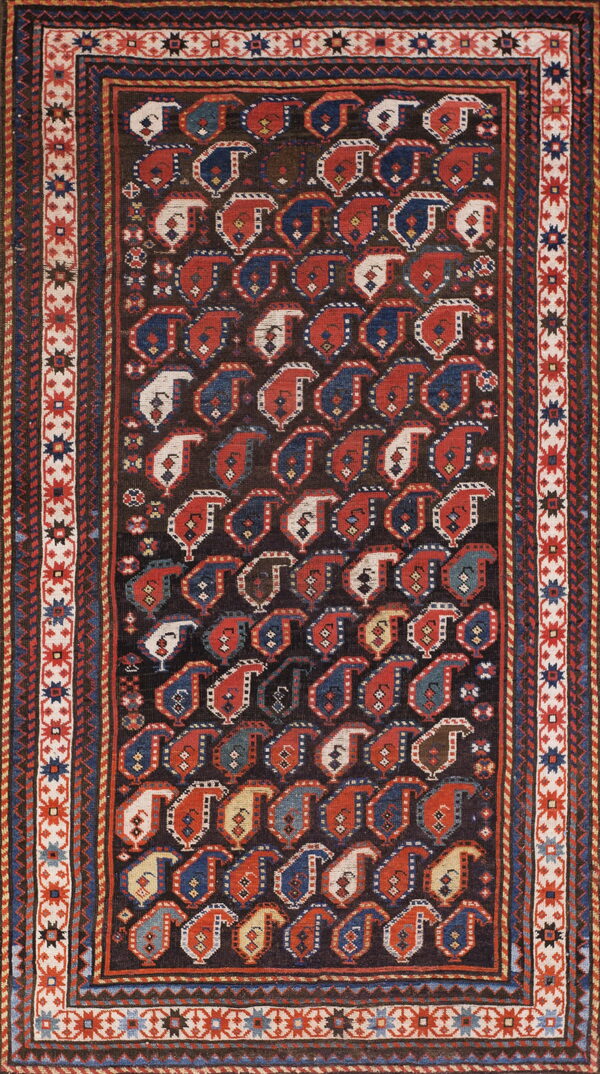 Low pile rug featuring repeating red, navy, and cream boteh designs on a deep brown field.