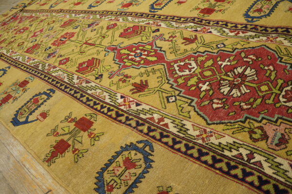 Golden yellow low-pile rug with intricate red, green, and blue geometric patterns on light wood flooring.