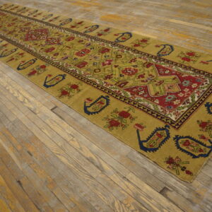 Gold runner rug with complex red, blue, and green geometric patterns on weathered wood planks.