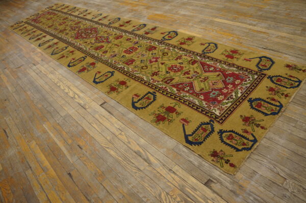 Gold runner rug with complex red, blue, and green geometric patterns on weathered wood planks.
