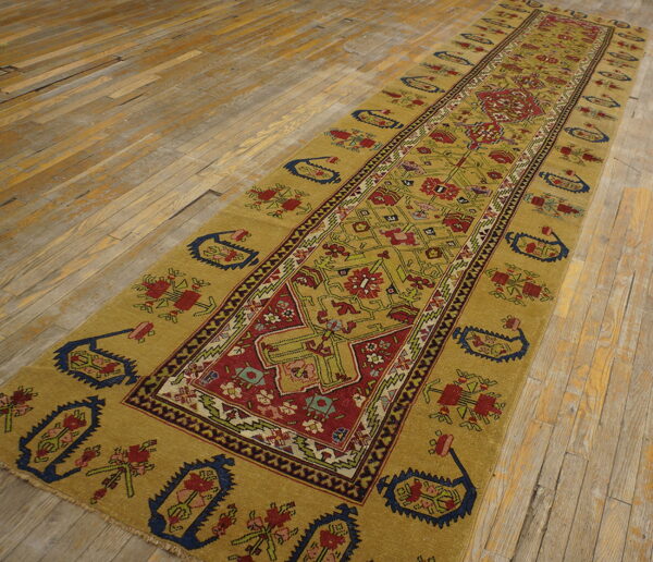 Gold and red traditional runner rug with a geometric pattern lies on rustic wooden flooring.