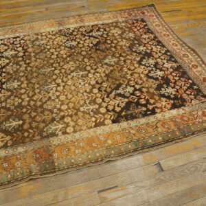 Traditional dark brown and khaki patterned rug with intricate borders lies on distressed wide plank flooring.