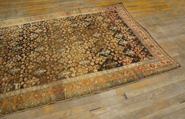 Traditional dark brown and khaki patterned rug with intricate borders lies on distressed wide plank flooring.