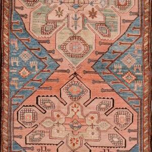 A long runner rug featuring alternating coral pink and slate blue geometric tribal medallions.