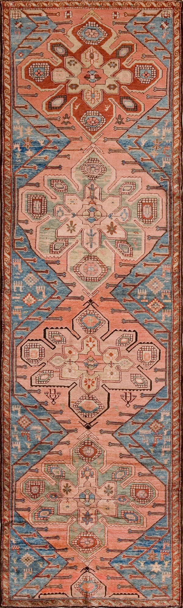A long runner rug featuring alternating coral pink and slate blue geometric tribal medallions.