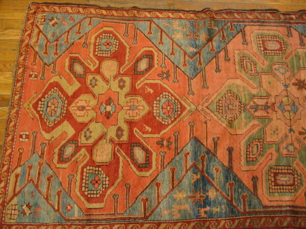 Geometric central medallion rug featuring orange, teal, and beige patterns on wood planks.