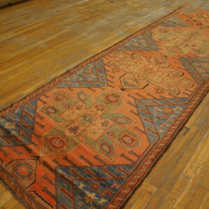 Geometric patterned runner rug in terracotta, dusty blue, and sage green on wide plank wood floors.