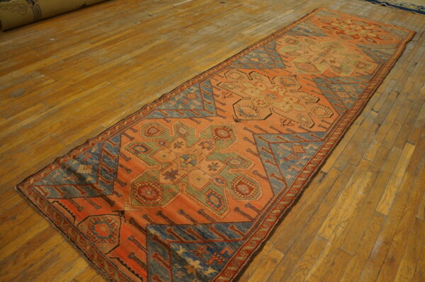 Geometric patterned runner rug in terracotta, dusty blue, and sage green on wide plank wood floors.