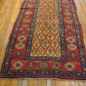 Red, navy, and gold tribal pattern runner rug with low pile on light hardwood flooring.
