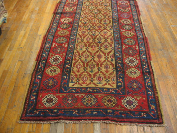 Red, navy, and gold tribal pattern runner rug with low pile on light hardwood flooring.