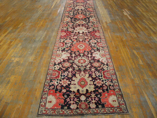 Traditional floral runner in navy, coral, and cream colors stretching across a distressed wooden floor.